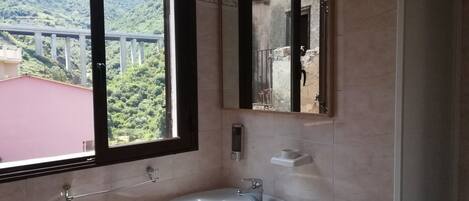Un baño con un ventanal grande, un lavabo y un espejo.