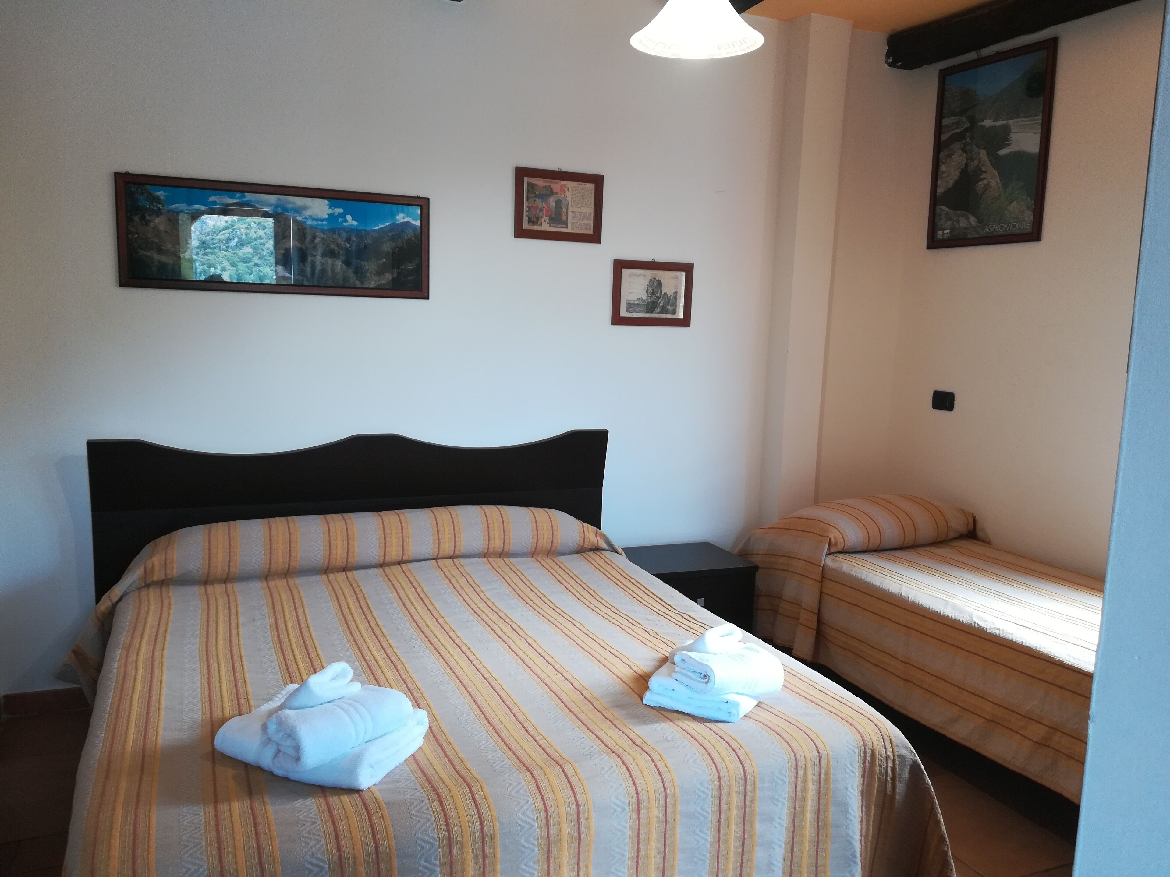 Une chambre d’hôtel avec un grand lit, un lit plus petit et deux tableaux encadrés au mur.