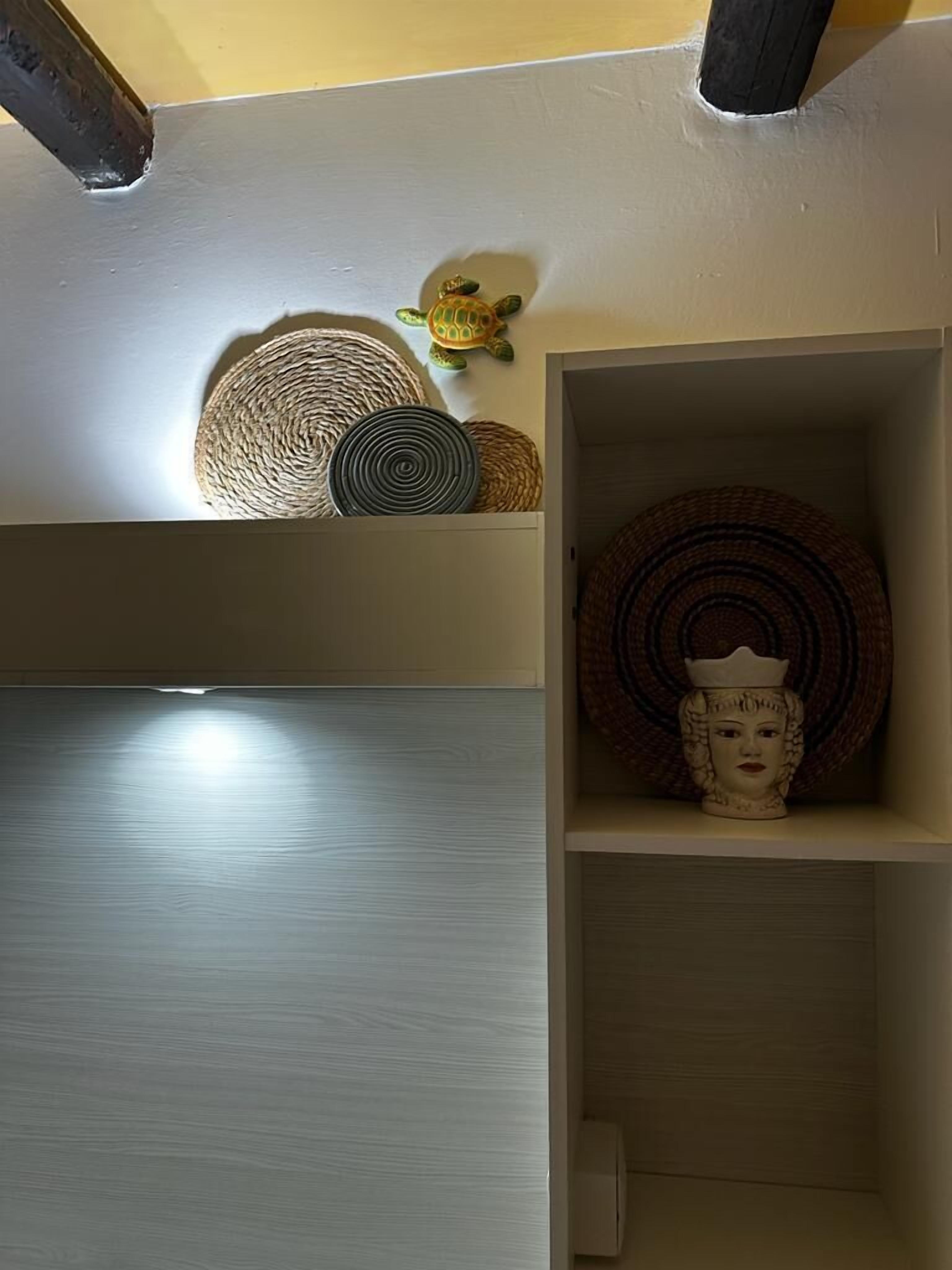 Una habitación con piso de madera brillante, una estantería con cestas tejidas y un objeto decorativo.