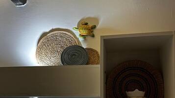 Una habitación con piso de madera brillante, una estantería con cestas tejidas y un objeto decorativo.