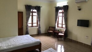 Une chambre avec deux lits, une chaise, une petite table et un téléviseur.
