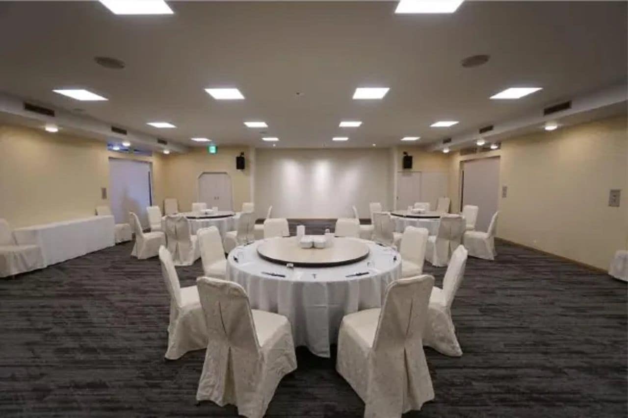 Ein Konferenzraum mit einem runden Tisch, Stühlen, Teppichboden und einer schlichten Wand mit einer Tür.