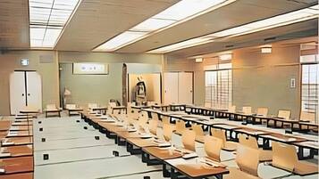 A conference room with long tables and chairs, a projector screen, and a large window.