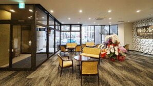 A hotel lobby with a glass partition, seating area, and a floral arrangement. - Utsunomiya Hotel Maruji (Utsunomiya)