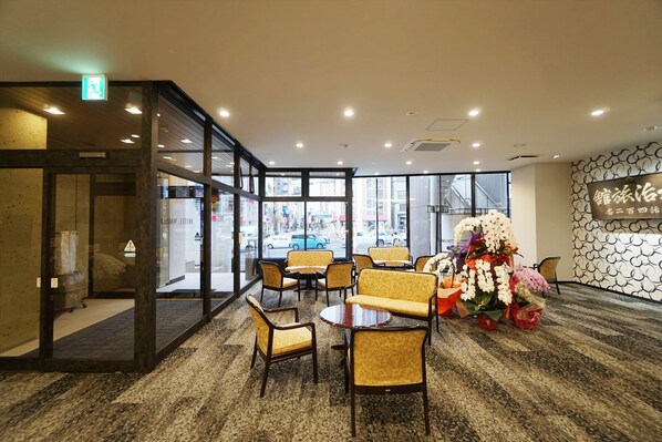 A hotel lobby with a glass partition, seating area, and a floral arrangement. - Utsunomiya Hotel Maruji (Utsunomiya)