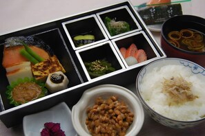 A bento box with various food items including fish, vegetables, and rice. - Utsunomiya Hotel Maruji (Utsunomiya)