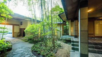 A traditional Japanese building with a stone pathway, bamboo trees, and a tiled entrance.
