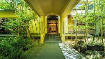 A pathway leading to a building entrance with steps and greenery on either side.