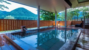 Una piscina cubierta al aire libre con terraza de madera y vistas a un paisaje montañoso.