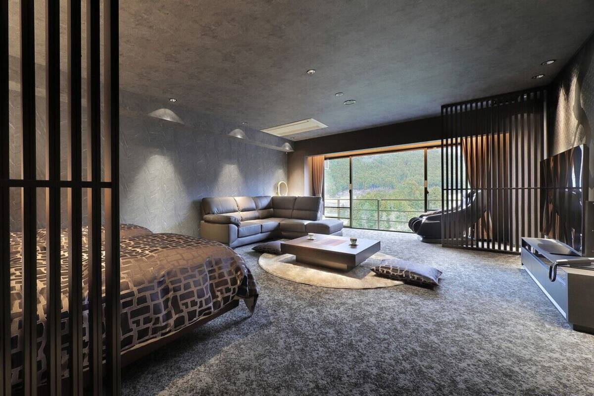 Une chambre moderne avec un lit, un canapé et une grande fenêtre.