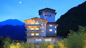 A multi-story hotel with a central tower, balconies, and a mountain backdrop. - Wakatake no Sho (Nikko)