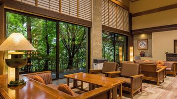 A room with large windows, a wooden table, and seating arrangements.