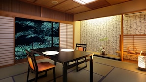 A traditional Japanese room with tatami flooring, a low table with cushions, a sliding door with a view of greenery, and a shoji screen with bamboo patterns. - Wakatake no Sho (Nikko)