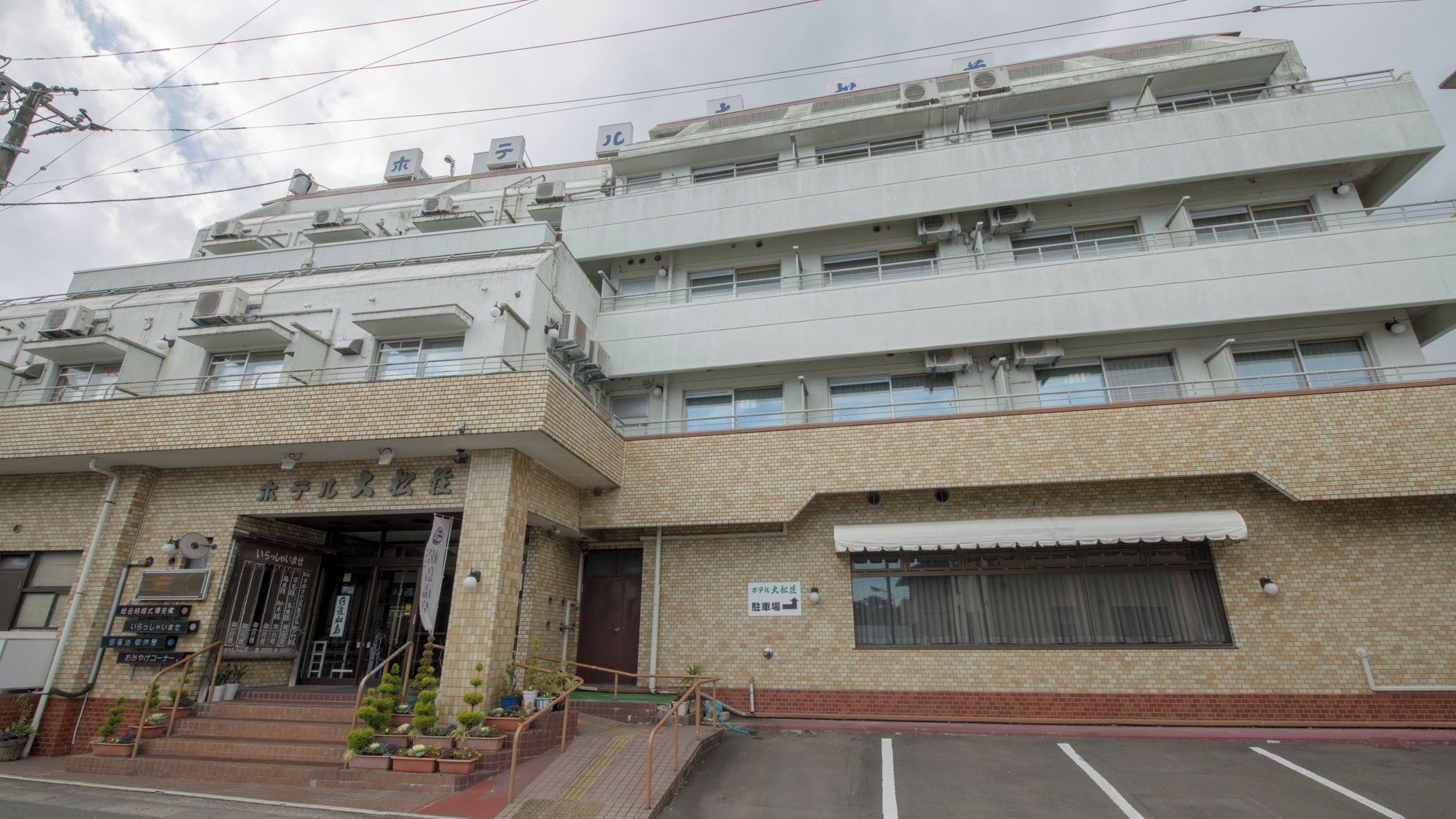 A multi-story building with a brick facade, a gated entrance, and a parking area.