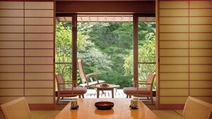 A traditional Japanese room with tatami flooring, a low table with a bowl, and a view of lush greenery through large sliding doors. - Shofurou Matsuya (Nasushiobara)