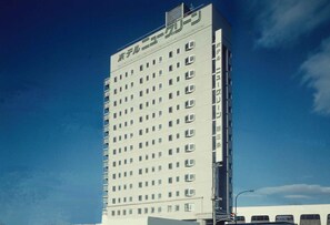 Un edificio alto de varios pisos con una fachada uniforme y numerosas ventanas.