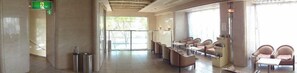 A hotel lobby with a reception desk, seating area, and large windows.