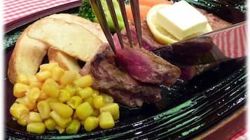 A meal with a fork, including meat, corn, and a slice of bread.
