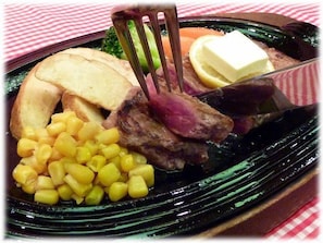 A meal with a fork, including meat, corn, and a slice of bread.