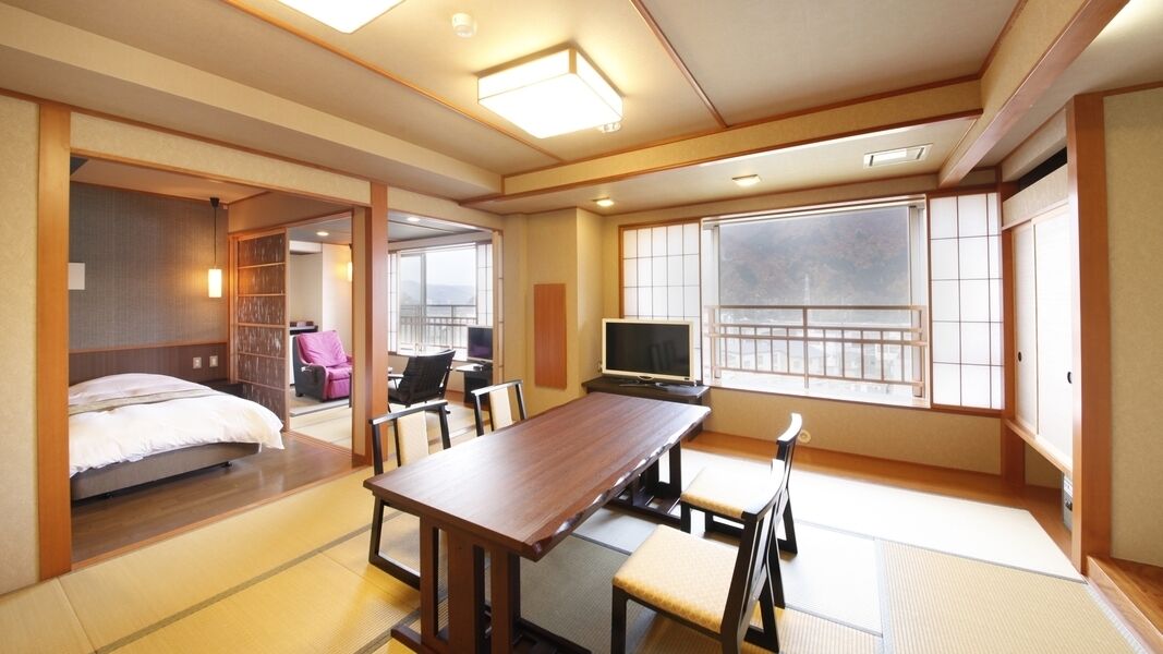 A traditional Japanese room with tatami flooring, a bed, a TV, and a balcony with a view.