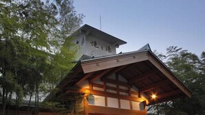 Un edificio tradicional japonés con estructura de madera, entrada de tejas y un letrero con caracteres japoneses.