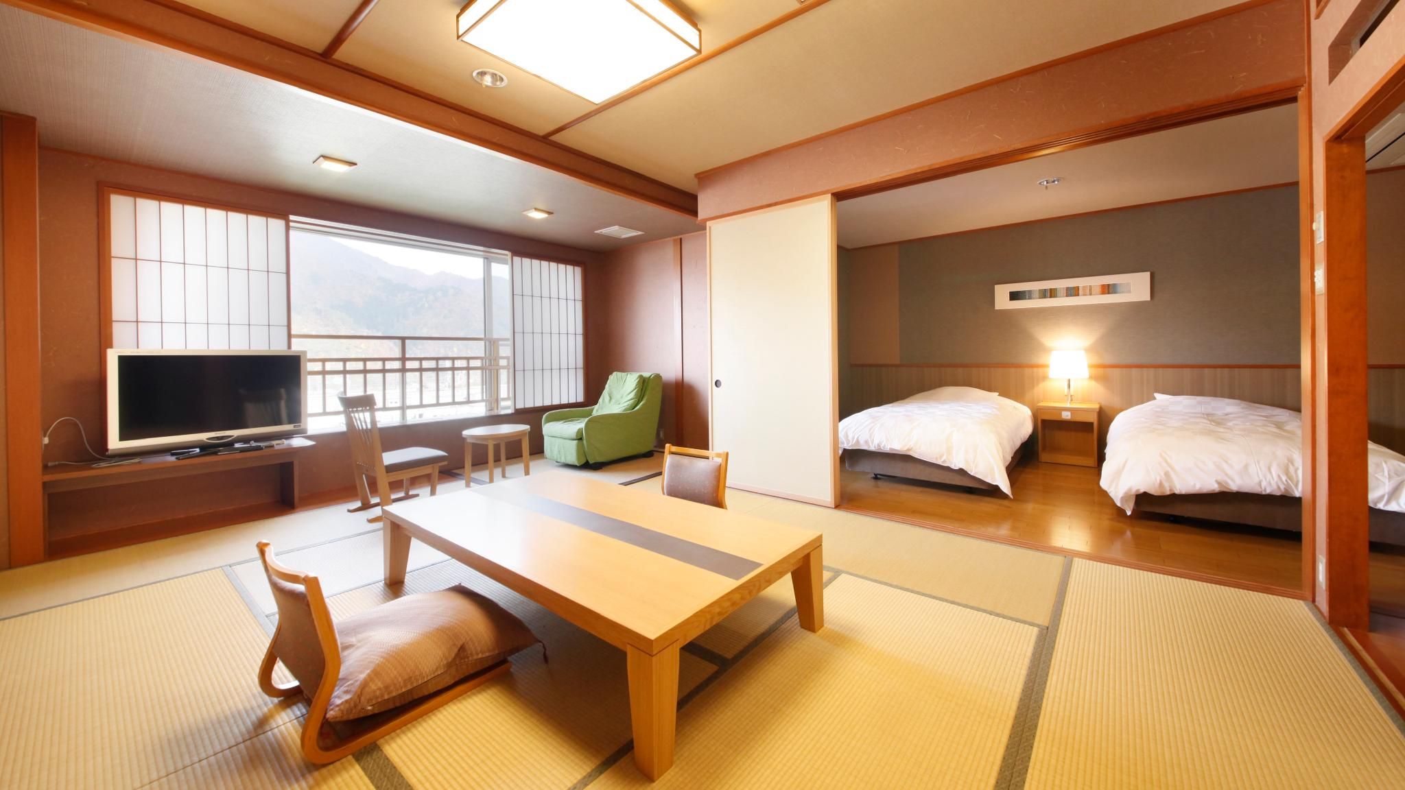 Een traditionele Japanse kamer met tatami vloerbedekking, een lage tafel, een televisie en een bed met nachtkastje.