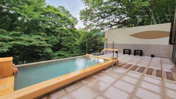 Ein Pool im Freien mit Holzterrasse, umgeben von üppiger Vegetation.