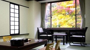 A traditional Japanese-style room with tatami flooring, a low table, and a view of autumn foliage through large windows. - Shiobara Onsen Okushiobara Kogen Hotel (Nasushiobara)