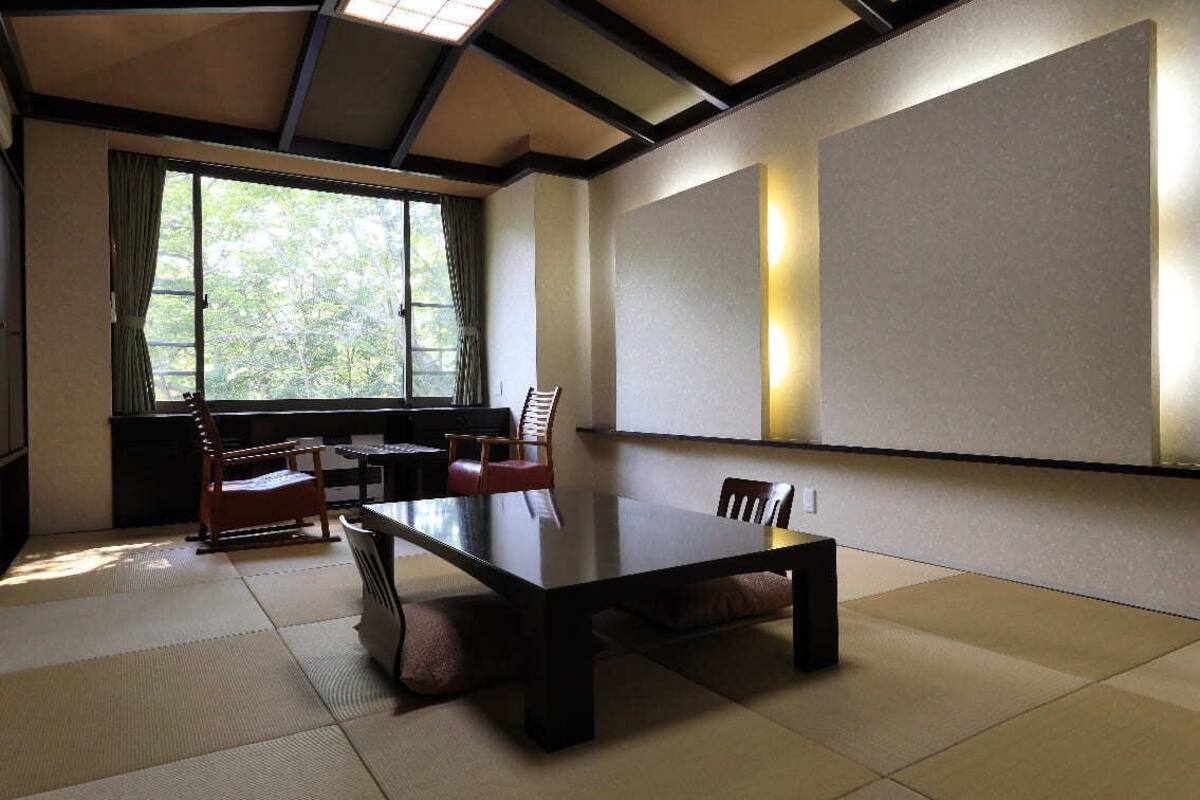 A traditional Japanese-style room with tatami flooring, a low table, and chairs.