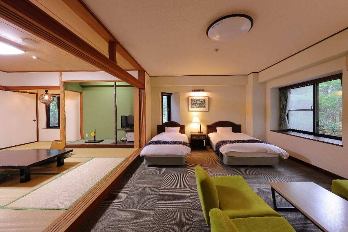 A hotel room with two beds, a dining table, and a sofa.