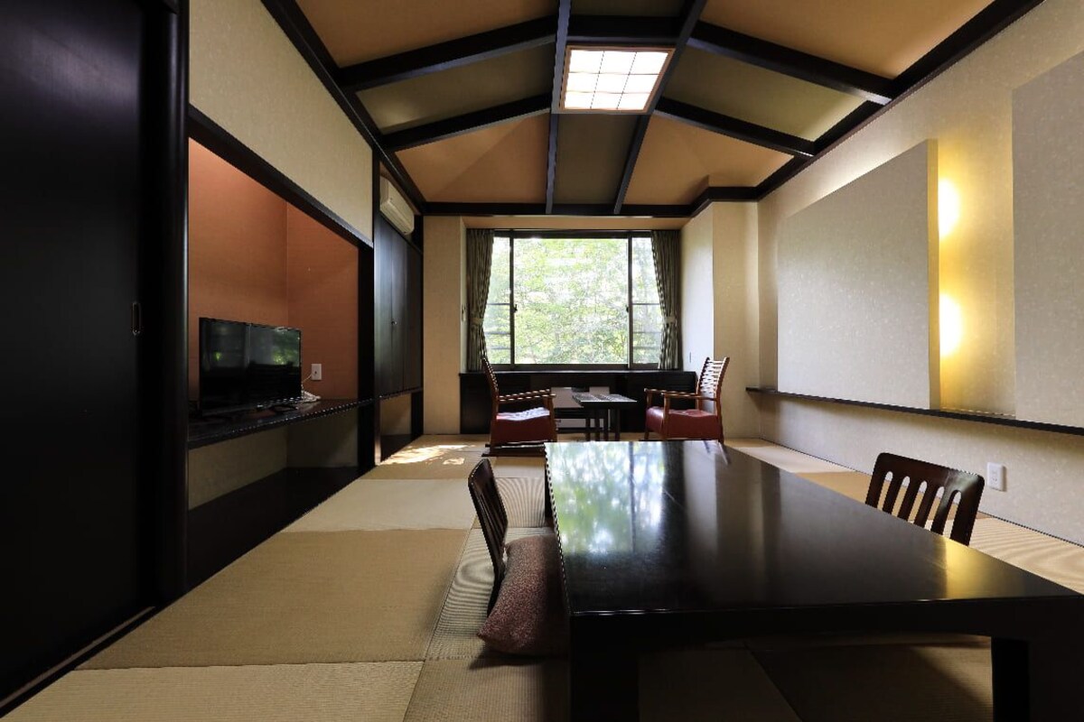 A traditional Japanese-style room with tatami flooring, a low table, and a television.
