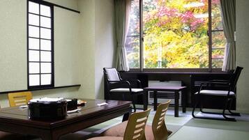 A traditional Japanese-style room with tatami flooring, a low table, and chairs.