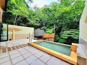 A modern outdoor hot tub area with a wooden deck, surrounded by lush greenery. - Shiobara Onsen Okushiobara Kogen Hotel (Nasushiobara)