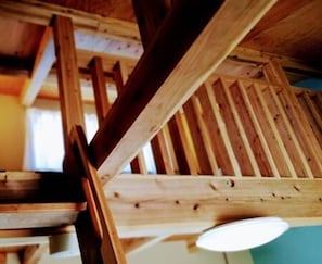 Een houten trap met een leuning en een lamp bovenin.