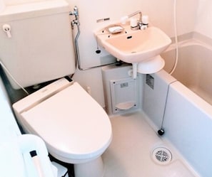 Een kleine, functionele badkamer met toilet, wastafel en douche.