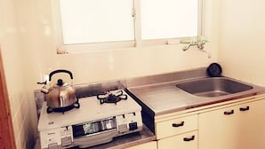 Een keuken met een waterkoker, een koffiezetapparaat en een spoelbak.