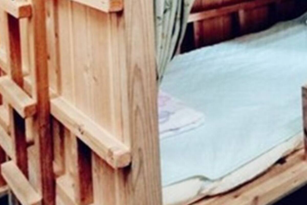 Een houten stapelbed met een matras en kussen.