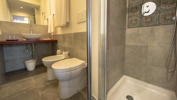 A modern bathroom with a glass-enclosed shower, a double sink vanity, and a toilet. - B&B Roma 474 (Rome)