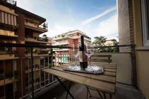 Un balcón con una mesa para dos, una botella de vino y dos copas de vino.