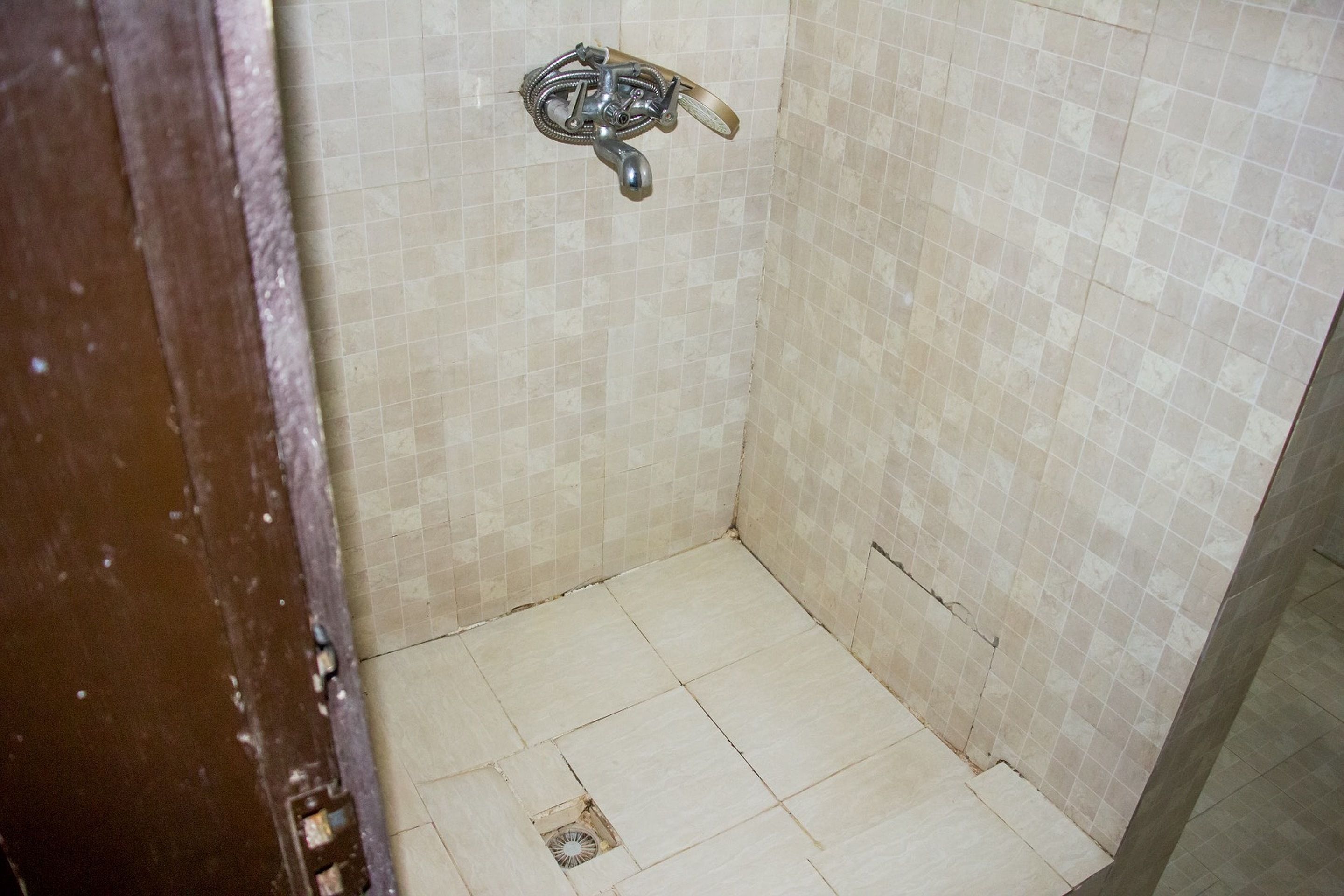 A small, tiled bathroom with a shower area and a visible drain.