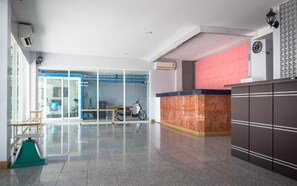A hotel lobby with a reception desk, a glass door entrance, and a scooter parked inside. - Bird Room Hotel (Bangkok)