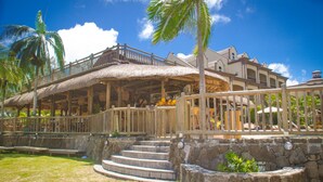Ein Resort mit einem reetgedeckten Gebäude, Steinstufen und Palmen.
