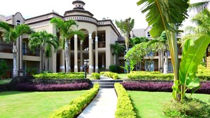 Ein Hotel mit Innenhof, Palmen und einem symmetrisch angelegten Garten.
