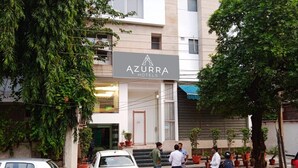 A hotel named Azurra with a modern facade, a visible entrance, and potted plants around the building. - Azurra Hotels (New Delhi)