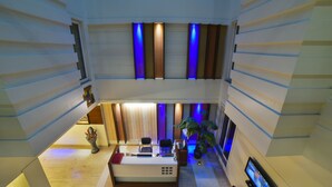 A modern reception area with a desk, chairs, and a potted plant. - Azurra Hotels (New Delhi)
