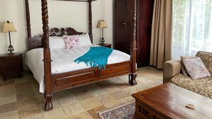 A four-poster bed with a wooden frame, two bedside tables with lamps, a patterned throw blanket, and a patterned sofa. - 42onKing (Centurion)