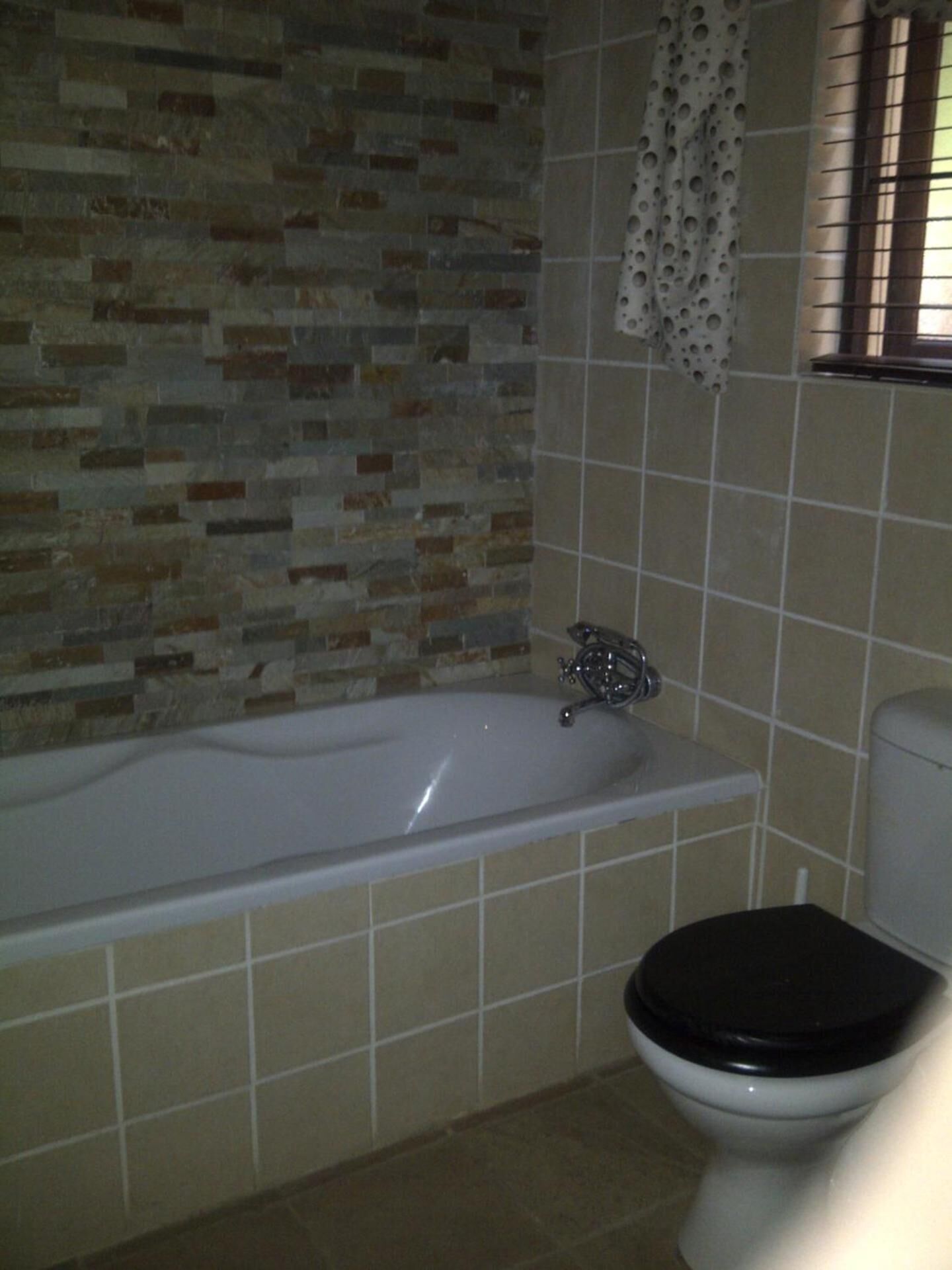 A bathroom with a bathtub, toilet, and tiled walls.