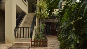 A courtyard with a staircase, a wooden fence, and various plants. - 42onKing (Centurion)
