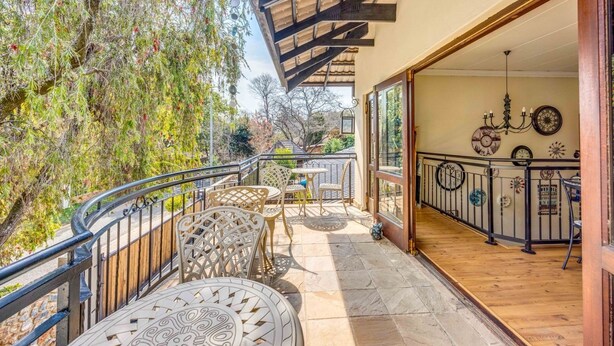 A balcony with outdoor seating, a wooden ceiling, and a view of trees. - 42onKing (Centurion)