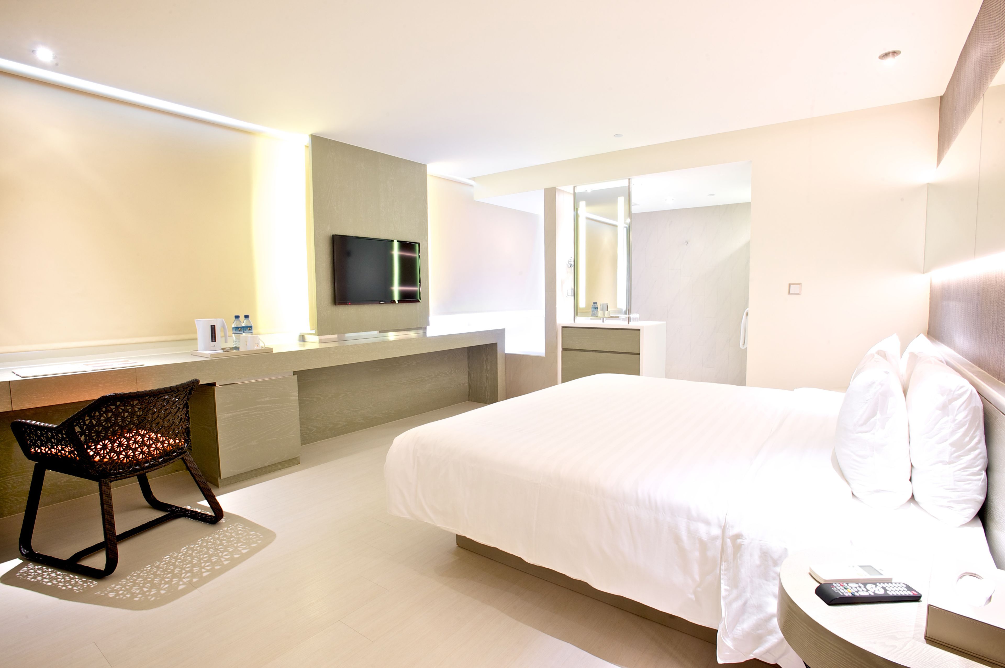 Een moderne hotelkamer met een groot bed, een bureau met stoel, een flatscreen-tv en een badkamer met spiegel.